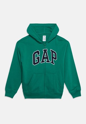 Sweat à capuche zippé vert avec poches avant et capuche, avec de grandes lettres "GAP" noires et blanches sur la poitrine.