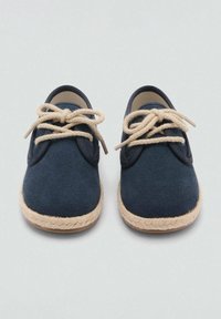 Námořnické semišové boty s kulatou špičkou, gumovou podešví a hnědými pletenými juty akcenty. Obsahují béžové šnůrky a měkkou podšívku uvnitř.