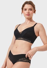 Černý krajkový bralet s nastavitelnými ramínky a výstřihem do V. V kombinaci s odpovídajícími černými kalhotkami s krajkovými akcenty po stranách.