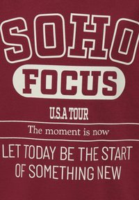 Bordo puuvillane T-särk, millel on valge tekst: "SOHO FOCUS", "U.S.A TOUR" ja "LAS KÄESOLEV PÄEV OLGU UUE ASJA ALGUS." Julge, graafiline disain.