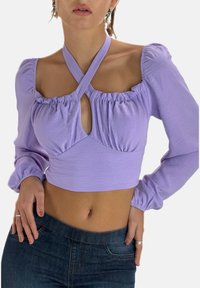 Lavendel langærmet crop top med puffede ærmer, rynket detaljering og en nøglehulåbning foran, fremstillet af blød, tekstureret stof.