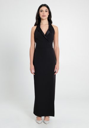 Schwarzes Halterneck-Abendkleid mit einer figurschmeichelnden Silhouette, das einen Satin-Kragen und einen bodenlangen Schnitt aufweist. Akzentuiert mit silbernen High-Heels.