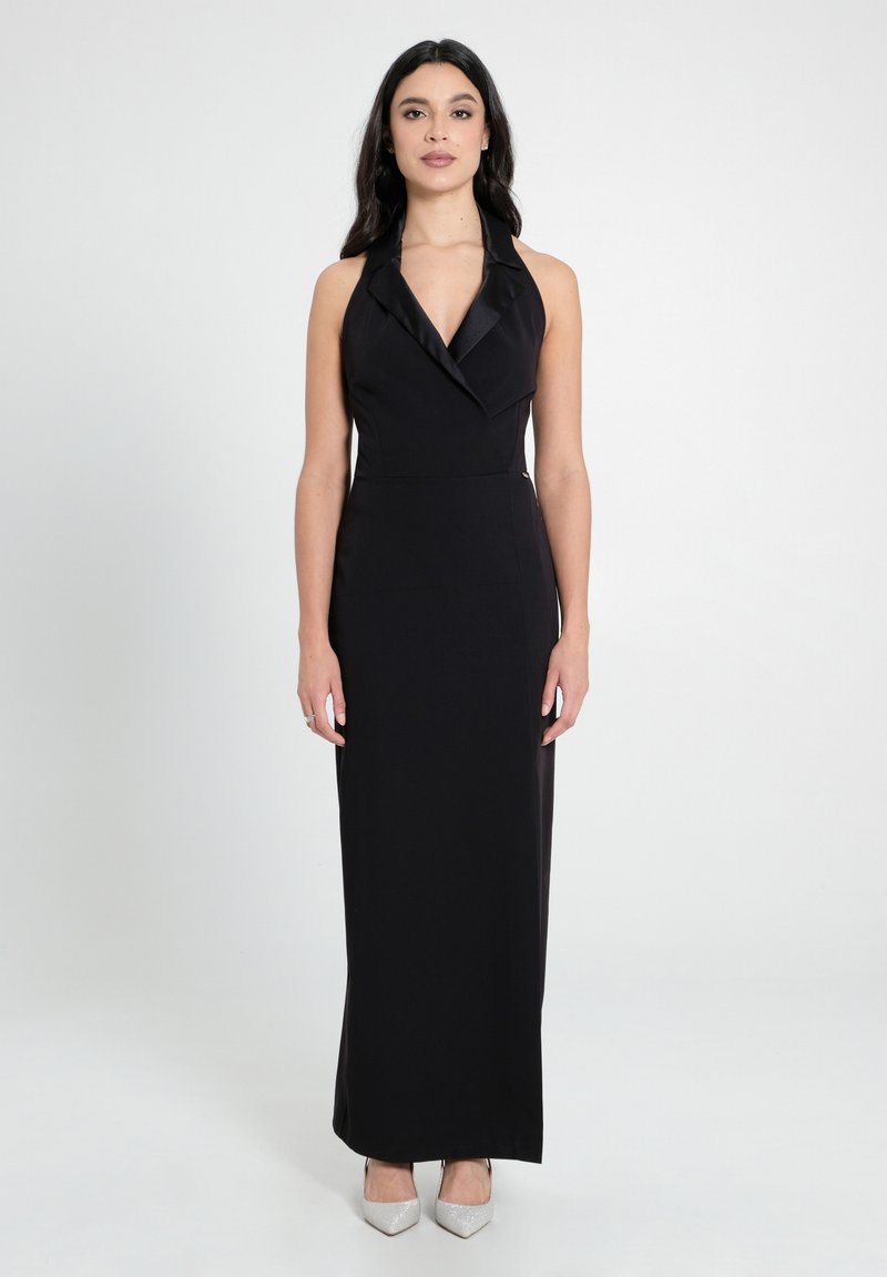 Schwarzes Halterneck-Abendkleid mit einer figurschmeichelnden Silhouette, das einen Satin-Kragen und einen bodenlangen Schnitt aufweist. Akzentuiert mit silbernen High-Heels.