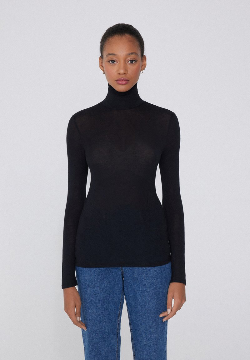 Schwarzes langärmliges Turtleneck-Oberteil aus transparenter Stoff, passgenaues Design, mit glatter Textur und schlichter Optik, kombiniert mit blauen Jeans.