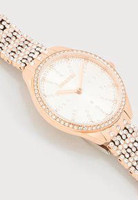 Ρολόι χειρός Swarovski σε ροζ χρυσό με στεφάνι και μπρασελέ διακοσμημένα με κρύσταλλα, λευκό καντράν με δείκτες ώρας από κρύσταλλα και τρία δείκτες που δείχνουν 10:10:30.