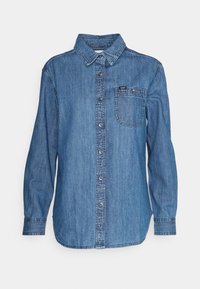 Blå denimskjorta med långa ärmar, knappstängning fram, en bröstficka och märkesetikett på fickan. Klassisk krage.