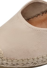 Beige mokkasiinit nilkkureilla, jossa on pyöreä kärki, juuttireunus ja pehmeä sisäpinta. Ylämateriaali on sileä ja tekstuuri.