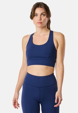 Navy blue sports bra featuring a scoop neckline, thick straps, and seamless design. Made from stretchy, moisture-wicking fabric.
