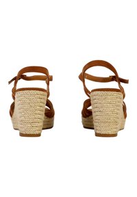 Sandali wedge in pelle marrone con tacco in juta intrecciata, apertura sul retro e cinturini regolabili alla caviglia. Materiale testurizzato con dettagli intrecciati.