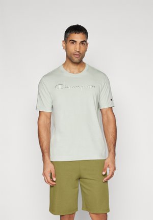 Light green cotton t-shirt with embroidered "Champion" logo in white, round neck, and short sleeves, paired with olive green shorts.
