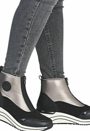 Des bottines noires et argentées métalliques avec une fermeture éclair, des panneaux texturés et une semelle compensée ornée de rayures blanches et d'une finition brillante.