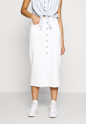 Jupe midi en denim blanc avec une fermeture à boutons sur le devant, des poches latérales et un design structuré. Associée à une chemise bleue rayée nouée et à des baskets blanches.