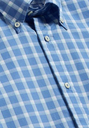 Chemise à carreaux bleue et blanche, boutonnée avec un col boutonné, présentant trois boutons blancs visibles le long de la patte de boutonnage avant.