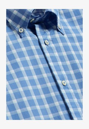Chemise à carreaux bleue et blanche, boutonnée avec un col boutonné, présentant trois boutons blancs visibles le long de la patte de boutonnage avant.