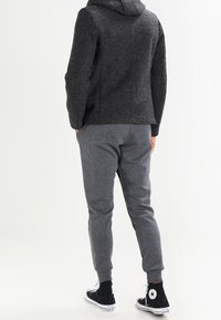 Grå uldblanding hoodie med en tekstureret overflade, parret med grå sweatpants og sorte høje sneakers. Minimalistisk design med lommer.