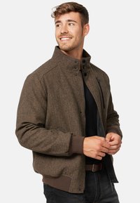 Brauner Fischgrät-Jacke mit hohem Kragen, Reißverschlussfront und Knopfakzenten. Mit gerippten Bündchen und Bund. Slim-Fit-Design.