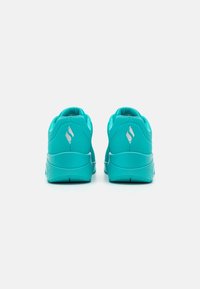 Turkosa sportskor med en elegant design, textilmaterial, kontrasterande detaljer och en rund häl. Har logotyp på hälen.