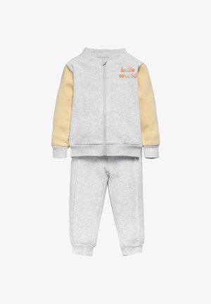 El chándal gris de algodón presenta una chaqueta con cremallera, mangas amarillas y el texto "hola mundo", combinado con pantalones a juego y puños acanalados.