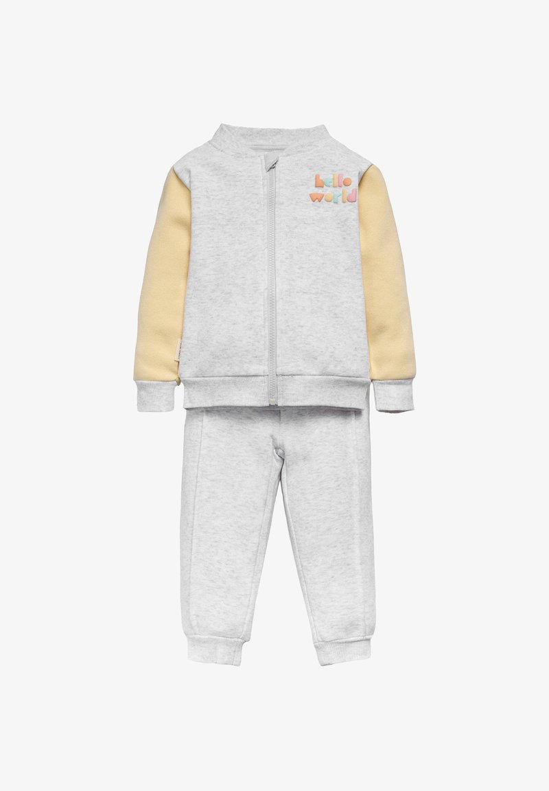 El chándal gris de algodón presenta una chaqueta con cremallera, mangas amarillas y el texto "hola mundo", combinado con pantalones a juego y puños acanalados.