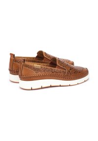 Brown leather slip-on shoes with intricate floral cut-out design, white sole, and decorative stitching along the edges.
