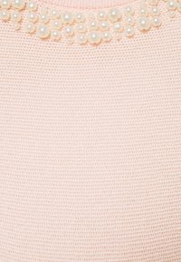 Tessuto lavorato a maglia rosa chiaro con una superficie testurizzata, impreziosito all'uscita del collo con perle finte rotonde lucide di diverse dimensioni.