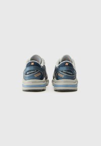 Chaussures de sport bleu et gris avec tige en mesh, col rembourré, marquage "New Balance" et "1000", et semelle en caoutchouc avec accents bleus.