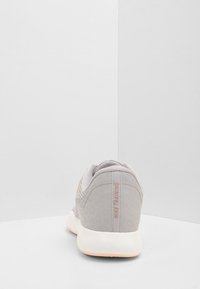 Szary but sportowy z siateczkową cholewką z wzorem lamparta, wyściełanym kołnierzem i białą podeszwą z jasnoróżowym akcentem.