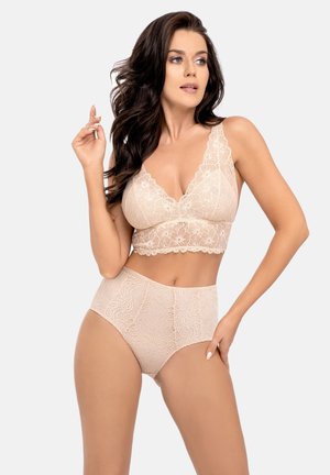 Kanten bralette in nude met golvende randen en bloemenpatronen, gecombineerd met bijpassende high-waisted slipjes in dezelfde stof en kleur.