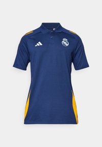 Polo bleu marine avec accents latéraux jaunes, col, logo Adidas sur le côté droit de la poitrine, et blason du Real Madrid sur le côté gauche de la poitrine.