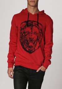 Roter Kapuzenpullover mit einem schwarzen Löwengrafik auf der Vorderseite. Verfügt über eine Kordelzugkapuze sowie gerippte Bündchen und Saum. Glattes Material aus Baumwollmischung.