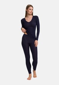 Marinblå långärmad topp med rundad halsringning, paired med tighta leggings. Båda i mjukt, elastiskt material med en slät yta.