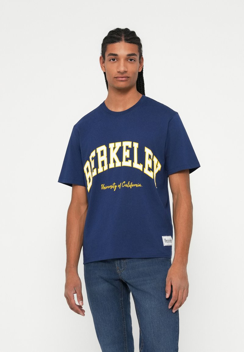 Navy modra bombažna majica s kratkimi rokavi, ki na sprednji strani vsebuje besedilo "BERKELEY University of California" v rumeni barvi; okrogli ovratnik in kratki rokavi.