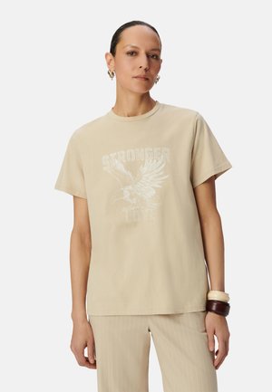 Beige cotton T-shirt with short sleeves, featuring a white graphic of an eagle above the text "STRONGER LOVE" printed on the front.