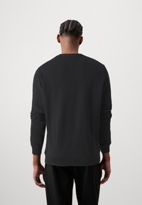 Sudadera negra con mangas largas y puños acanalados. Cuenta con un cuello redondo y una textura suave y lisa. Diseño simple, sin patrones ni adornos.