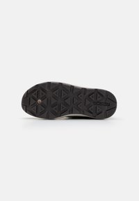 Semelle extérieure en caoutchouc noir avec un motif de traction multidirectionnel, comportant des formes triangulaires et rectangulaires, texturée pour une meilleure adhérence.