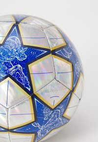 Blue soccer ball with iridescent surface, gold star patterns, and white illustrations. Includes "TRAINING" and "MATCH BALL REPLICA" text.