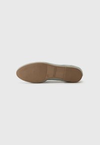 Baskets en daim bleu clair avec une semelle en caoutchouc brun texturé, présentant une forme épurée et des détails de conception minimaux.
