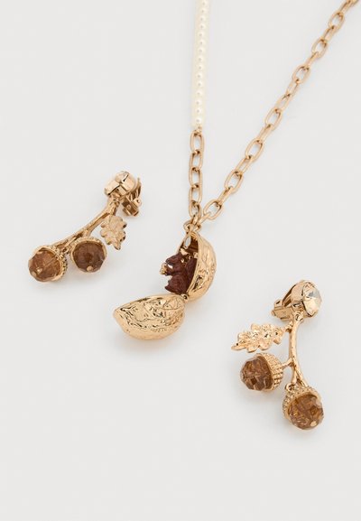 Κολιέ σε χρυσό τόνο με μενταγιόν καρυδιού με αρθρωτό καπάκι που αποκαλύπτει έναν σκιουράκι, συνδυασμένο με σκουλαρίκια σε χρυσό τόνο με βελανίδι και φύλλο.