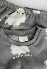 Vêtements pour bébé gris avec un imprimé fantôme et le texte "BABY BOO !" Comprend un col côtelé et une taille élastique.