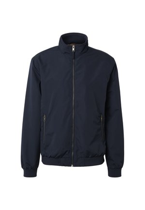 Tumši zila jaku ar rāvējslēdzēju, augstu apkakli, elastīgām aprocēm un apakšu, kā arī rāvējslēdzēja sānu kabatām, attēlota uz balta fona.