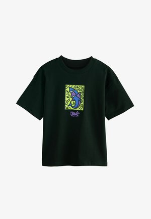 Kortærmet sort t-shirt lavet af bomuld, med et farverigt hajdesign på en grøn baggrund med dekorative linjer.