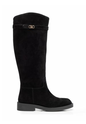 Czarny zamszowy kozak do kolan z niskim obcasem na słupku i małym złotym logo przy górnej krawędzi na pasku.