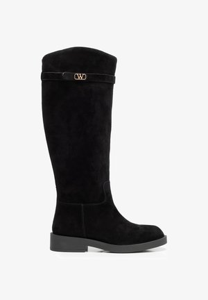 Czarny zamszowy kozak do kolan z niskim obcasem na słupku i małym złotym logo przy górnej krawędzi na pasku.