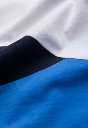 Tessuto di cotone con un design che presenta sezioni bianche, blu navy e due tonalità di blu, texture liscia e dettagli di cucitura visibili.