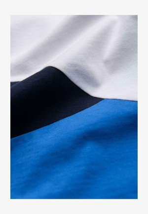 Tessuto di cotone con un design che presenta sezioni bianche, blu navy e due tonalità di blu, texture liscia e dettagli di cucitura visibili.