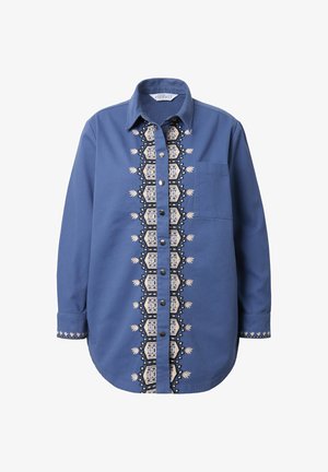 Sininen pitkähihaisista paita, napitus edessä ja keskellä brodeerattu geometrinen kuvio. Kengissä on rintatasku ja pehmeä kangastuntu.