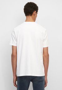 Witte katoenen t-shirt met korte mouwen en een ronde hals, met een eenvoudige, gladde structuur en een relaxte pasvorm. Geen zichtbare logo's of patronen.