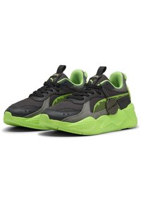 Baskets de sport noires et grises avec des accents vert néon, en maille texturée et matériaux synthétiques lisses, dotées d'une semelle épaisse et d'un système de laçage.