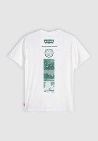 Hvit Levi's t-skjorte med grønn naturinspirert grafikk og teksten "En vei mot høyere læring" på baksiden.