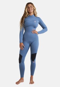 Blue wetsuit with long sleeves, featuring a textured pattern on one arm, black panel accents on thighs, and a small logo on the chest.